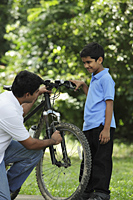 Father and son fixing bike together - Asia Images Group