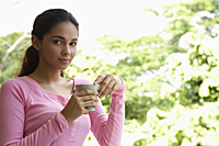 Young woman holding cup looking at camera - Asia Images Group