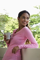 Young woman holding mug looking over shoulder - Asia Images Group
