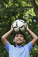 Young boy balances ball on his head - Asia Images Group