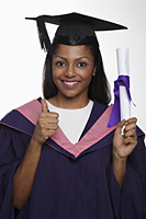 Young woman wearing cap and gown and holding diploma giving thumbs up sign - Asia Images Group