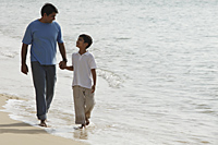 Father and son holding hands and walking on beach - Asia Images Group
