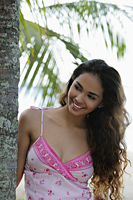 young woman smiling with long hair next to coconut tree - Asia Images Group