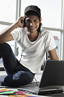 young man wearing headphones while on laptop - Asia Images Group
