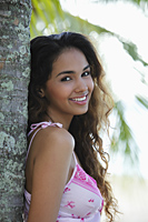 young woman leaning next to tree and smiling - Asia Images Group