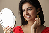 head shot of woman looking in the mirror and smiling - Asia Images Group