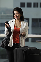 woman holding suitcase looking at phone and smiling - Asia Images Group