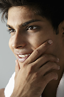 head shot of young man holding his chin and smiling - Asia Images Group