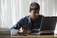young man looking at computer and studying - Asia Images Group