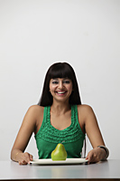 woman holding plate with green pear and smiling - Asia Images Group