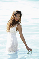young woman wearing a white dress and standing in water - Asia Images Group