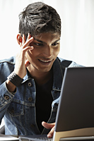 young man looking at laptop and smiling - Asia Images Group