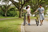Couple in park, holding bicycles, walking - Asia Images Group