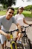 Young man and woman, on bicycles, looking at camera - Asia Images Group