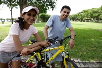 Couple leaning on bicycles, looking at camera - Asia Images Group