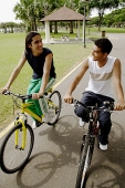 Two young men cycling side by side - Asia Images Group