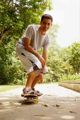 Man balancing on skateboard, looking at camera - Asia Images Group