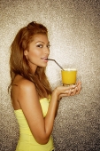 Young woman sipping drink with straw, looking at camera - Asia Images Group