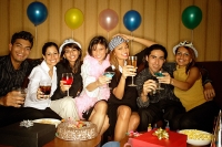 Young adults sitting side by side, celebrating, holding drinks - Asia Images Group