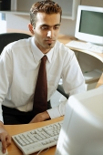Male executive at desk, using computer - Asia Images Group
