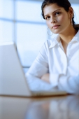 Female executive in front of laptop, looking at camera - Asia Images Group