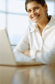 Female executive in front of laptop, smiling at camera - Asia Images Group