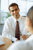 Male executive smiling at person in front of him, over the shoulder view - Asia Images Group