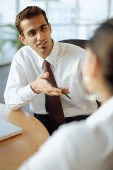 Male executive having discussion with person in front of him - Asia Images Group