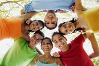 Group of young adults arms around each other, looking down at camera - Asia Images Group