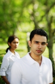 Man looking at camera, woman in the background - Asia Images Group