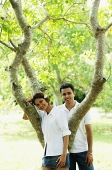 Couple looking at camera, tree between them - Asia Images Group