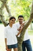Couple looking at camera, man leaning on tree - Asia Images Group