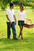 Couple walking in park, woman carrying picnic basket - Asia Images Group