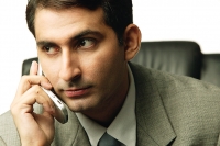 Businessman holding mobile phone, looking away - Asia Images Group