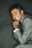 Businessman resting head on hands, smiling at camera - Asia Images Group