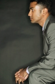 Businessman sitting, side view, hands clasped - Asia Images Group