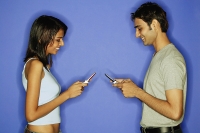 Couple face to face, holding mobile phones - Asia Images Group