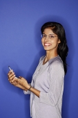 Woman looking at camera, holding mobile phone - Asia Images Group