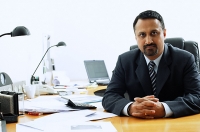 Businessman at desk, looking at camera - Asia Images Group