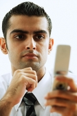 Executive looking at mobile phone, hand on chin - Asia Images Group