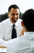 Two businessmen in office, talking face to face, over the shoulder view - Asia Images Group