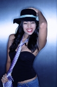 Young woman, wearing hat and tie, smiling, hand on head - Asia Images Group