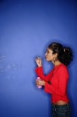 Woman blowing bubbles with bubble wand - Asia Images Group