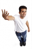 Man smiling at camera, arm outstretched, showing palm - Asia Images Group