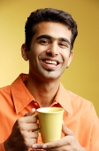 Man smiling at camera, mug in hand - Asia Images Group