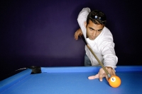 Young man preparing to hit pool ball - Asia Images Group