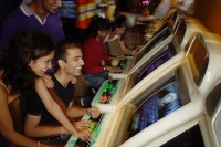 Young adults playing games in video arcade - Asia Images Group