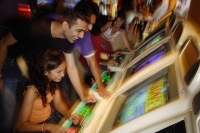Young adults in video arcade, playing games - Asia Images Group