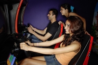 Young adults in a video game arcade, playing games - Asia Images Group