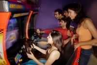 Young adults playing games in amusement arcade - Asia Images Group